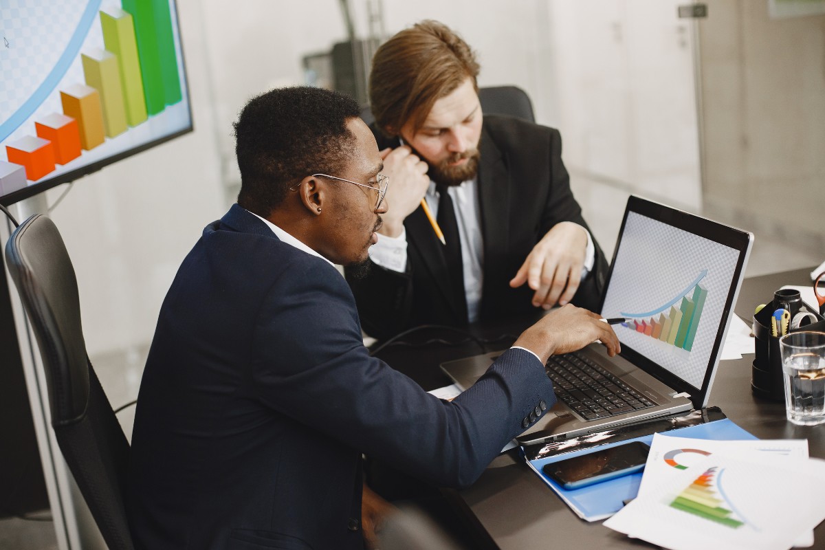 Dois consultores empresariais analisando gráficos de desempenho e crescimento em reunião estratégica.