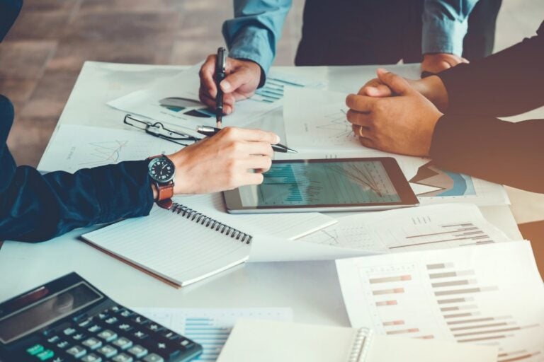 Equipe analisando relatórios e gráficos de contabilidade gerencial em reunião estratégica