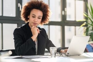 Gestora analisando relatórios financeiros no notebook, avaliando estratégias de crescimento empresarial