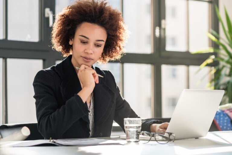 Gestora analisando relatórios financeiros no notebook, avaliando estratégias de crescimento empresarial