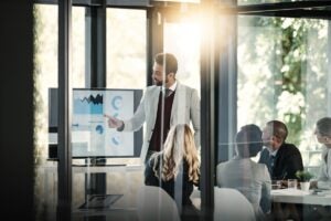 Consultor empresarial apresentando resultados e estratégias para equipe de gestores em reunião