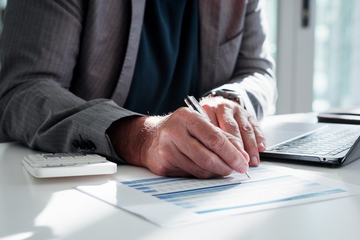Auditor analisando demonstrações contábeis e documentos financeiros de uma empresa.